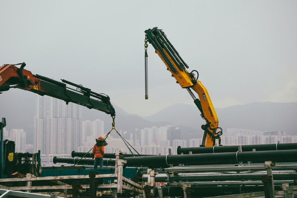 Construction crane lifting industrial pipes